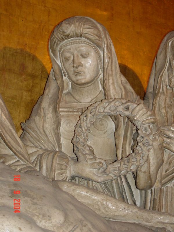 Certainly, this woman stands in the position of a wife, holding the crown of thorns as an honor.  She is not Mary, the mother, nor is she Mary Magdalene. She has an unusual dress of Celtic flavor, and wears a turban, unlike the other women.  This sculpture is traditionally said to have been 